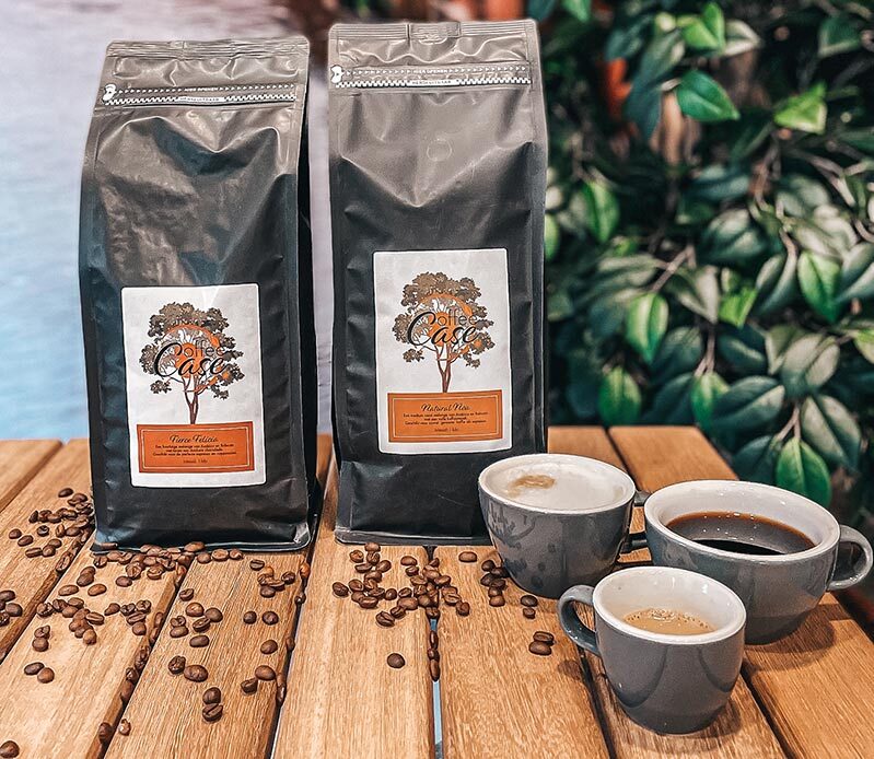 Afbeelding van een zak koffiebonen van CoffeeCase en kopjes koffie op tafel, met tips over waar je op moet letten bij het kiezen van lekkere koffiebonen voor je bedrijf.